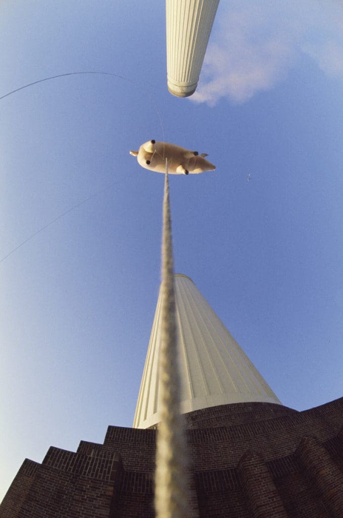 Photograph taken from below of the tethered pig floating between the two large chimneys at Battersea Power Station 1976 (c) Pink Floyd Music Ltd
